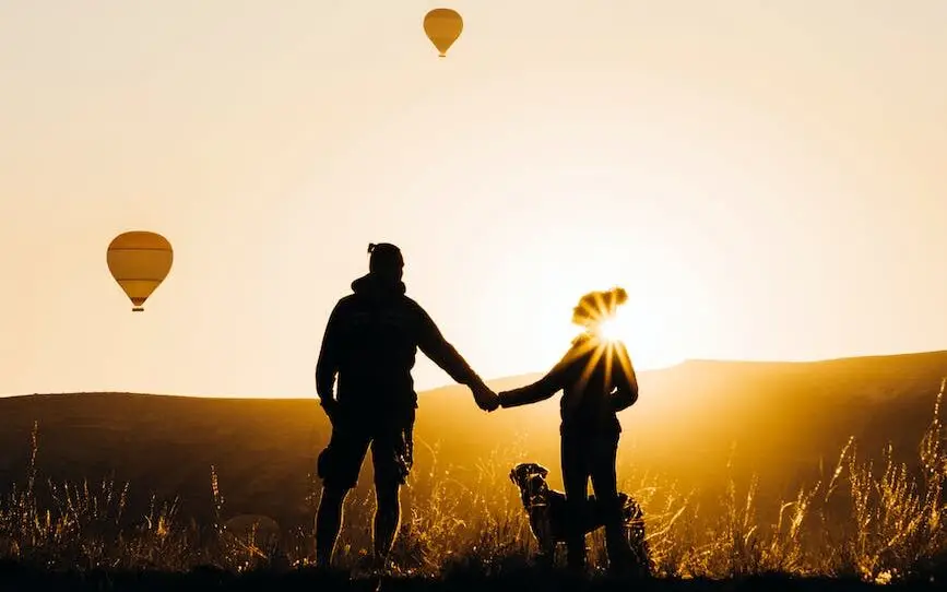 silhouette of a couple watching the flight of hot air balloons at sunrise to accompany a post about wellbeing